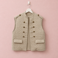 Chaleco acolchado beige colgado en una percha blanca sobre fondo rosa