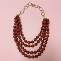 Collar Nashira terracota sobre fondo rosa pastel