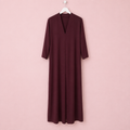 Vestido burdeos en percha sobre fondo rosa