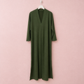Vestido verde oliva en percha sobre fondo rosa